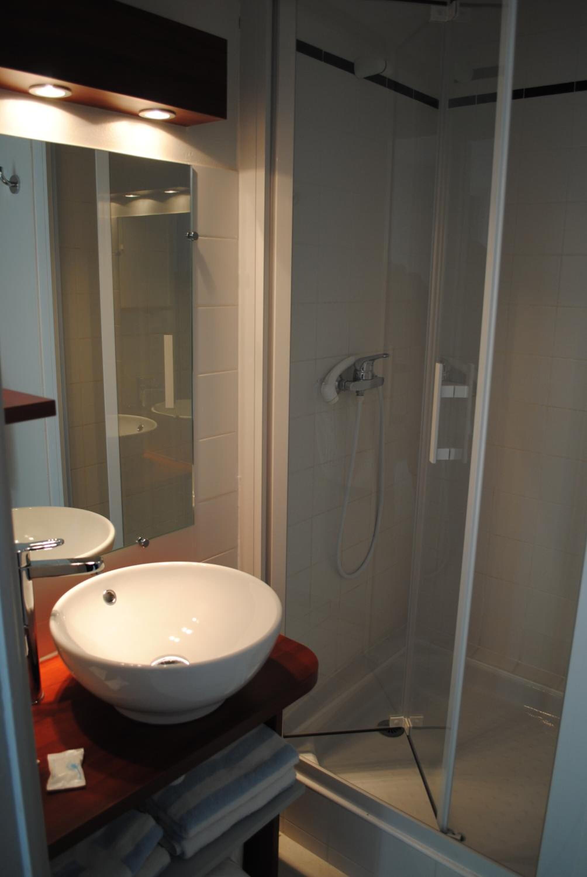 A bathroom with a white sink, a mirror, and a shower enclosure.