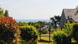 Zona residencial con una casa, jardín cercado y vista al mar.