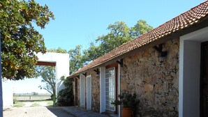 A stone building with a tiled roof, a potted plant, and a pathway leading to a white building. - Estancia Los Platanos (Valentines)