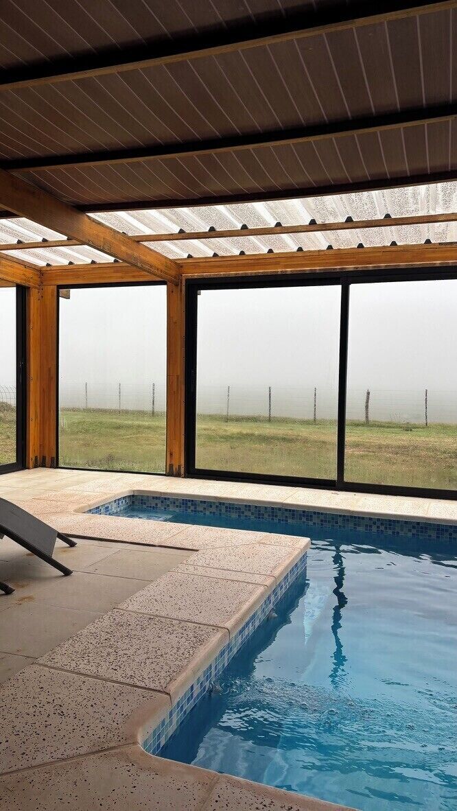 Piscina com vista para um campo gramado e cerca.