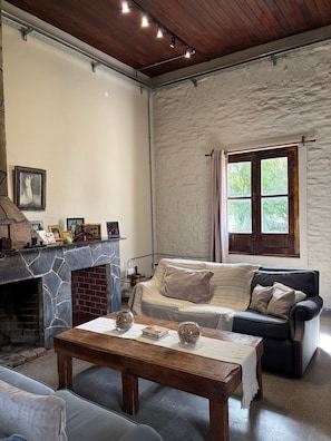 A cozy living room with a stone fireplace, a sofa, and a coffee table. - Estancia Los Platanos (Valentines)