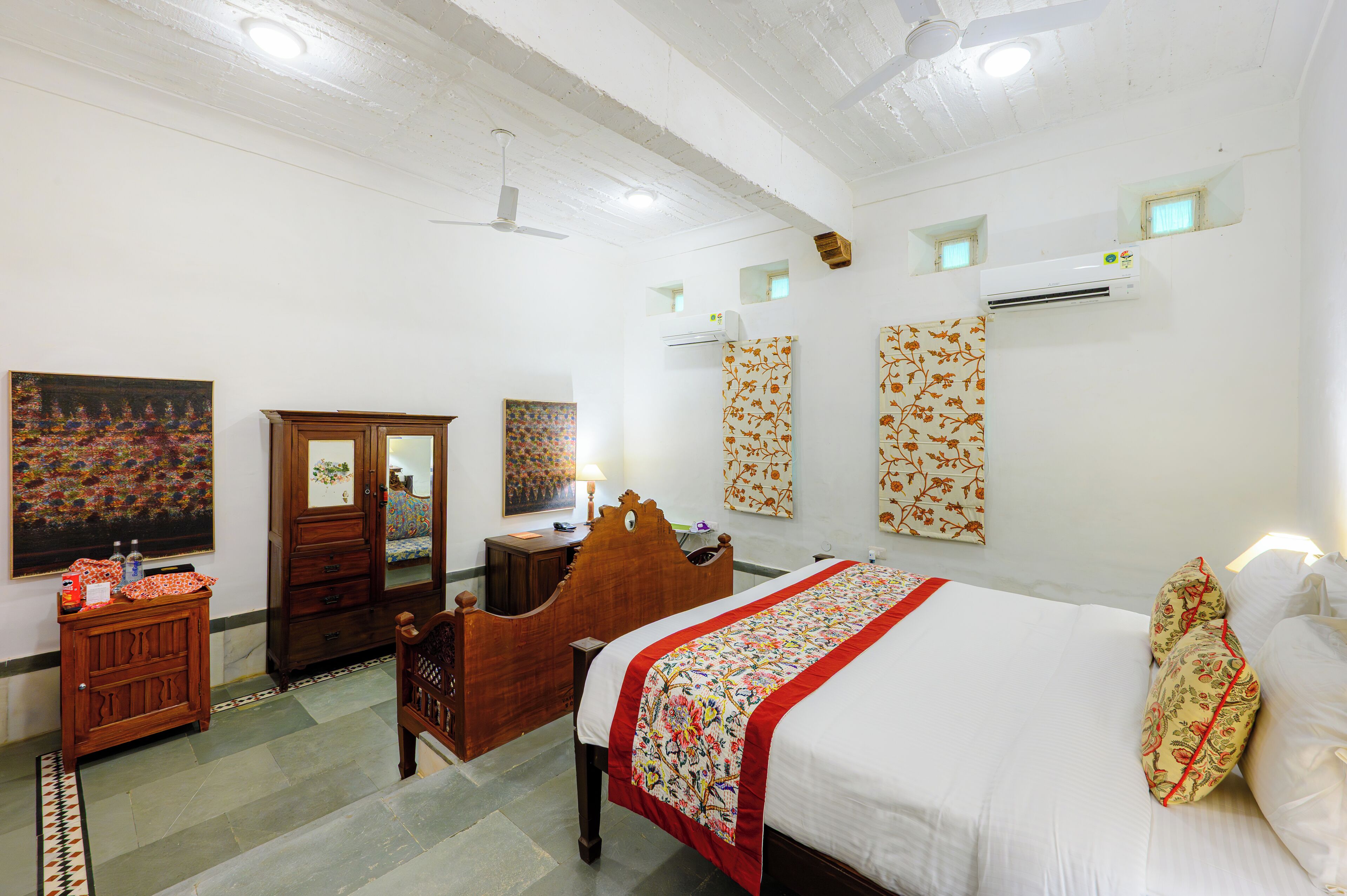 A hotel room with a bed, a wooden wardrobe, a desk, and a chair.