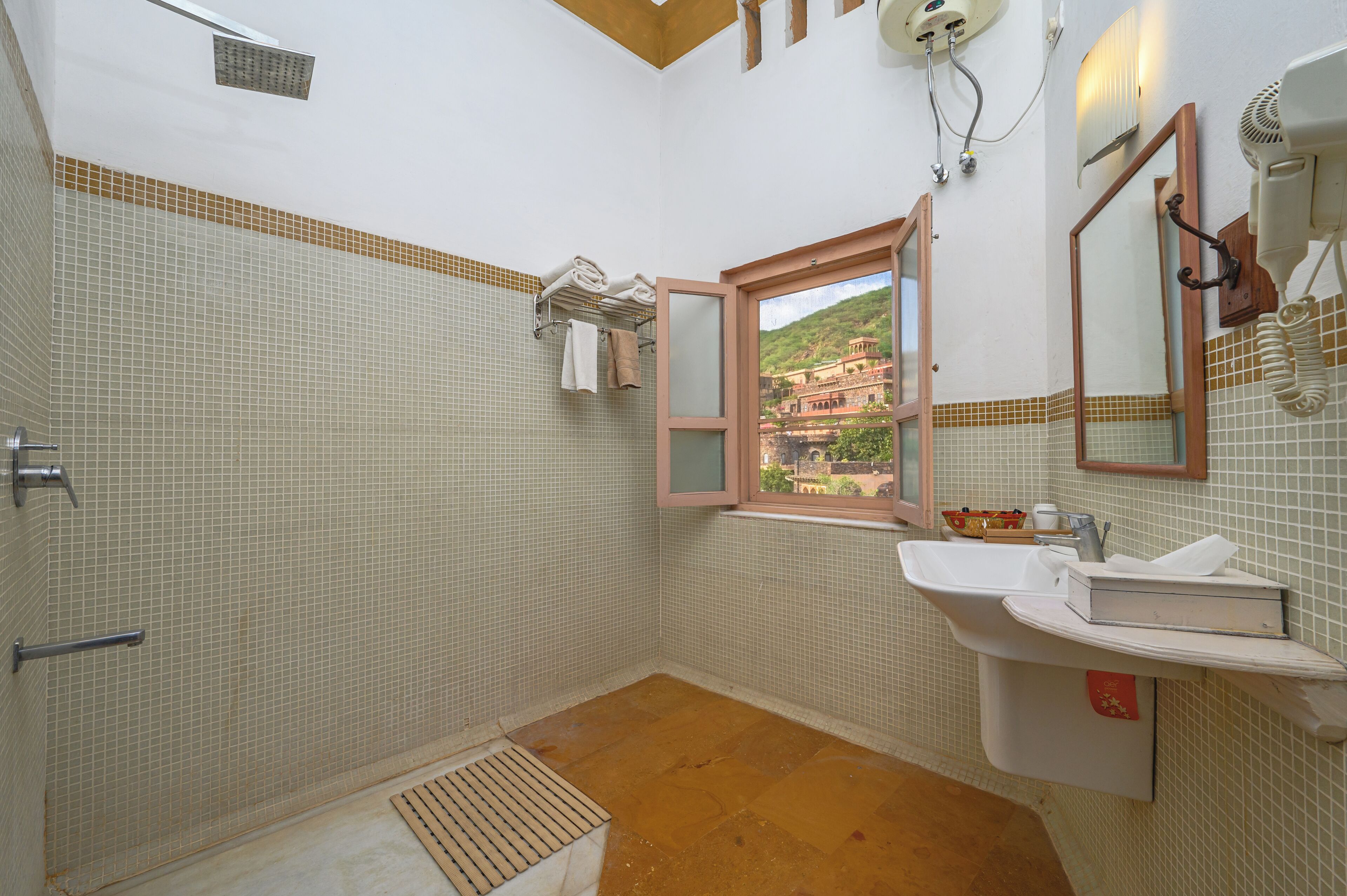 A bathroom with a shower, a sink, a window with a view, and a towel rack.