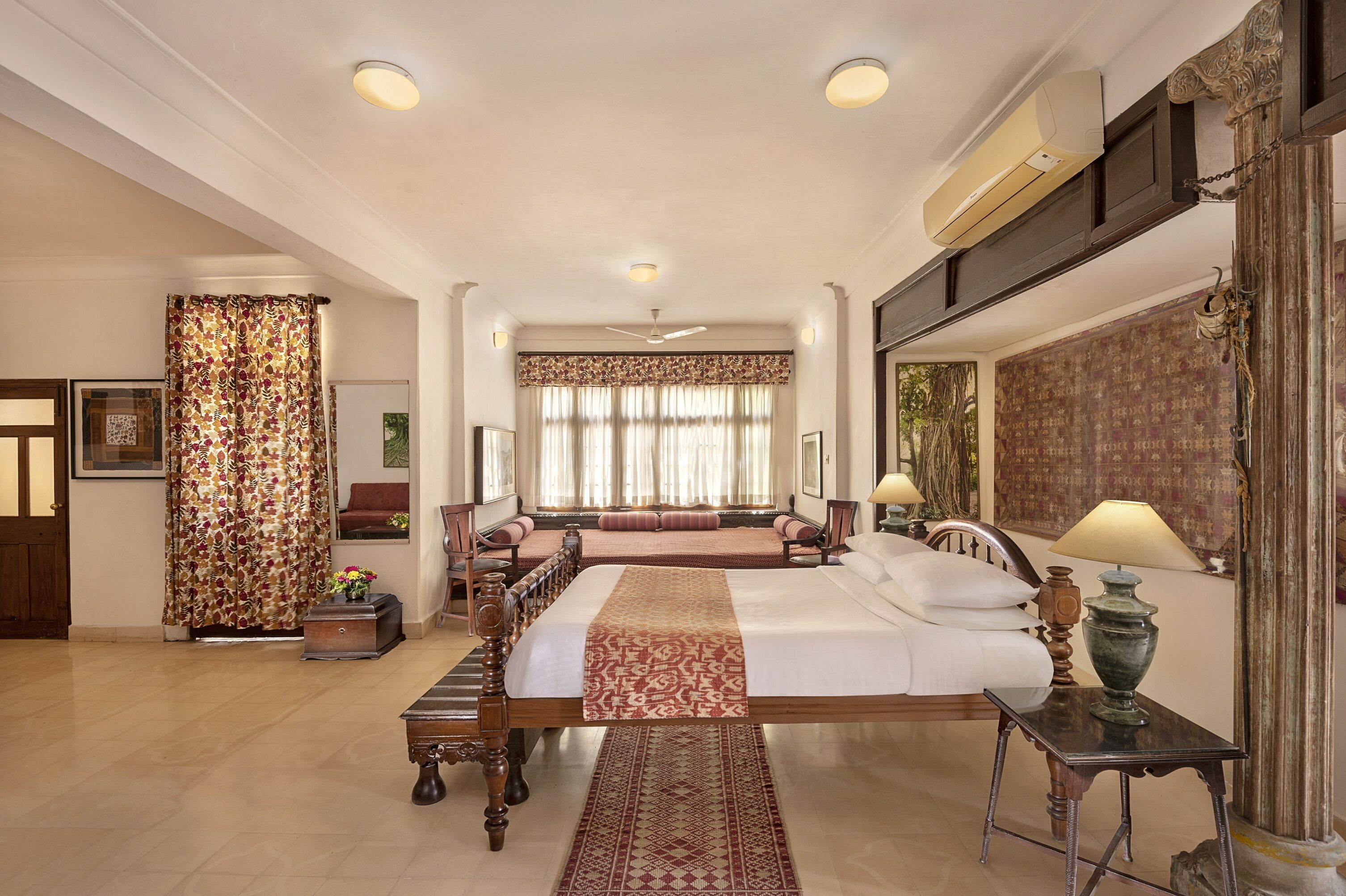 A spacious hotel room with a large bed, a sitting area, and a view of the city.