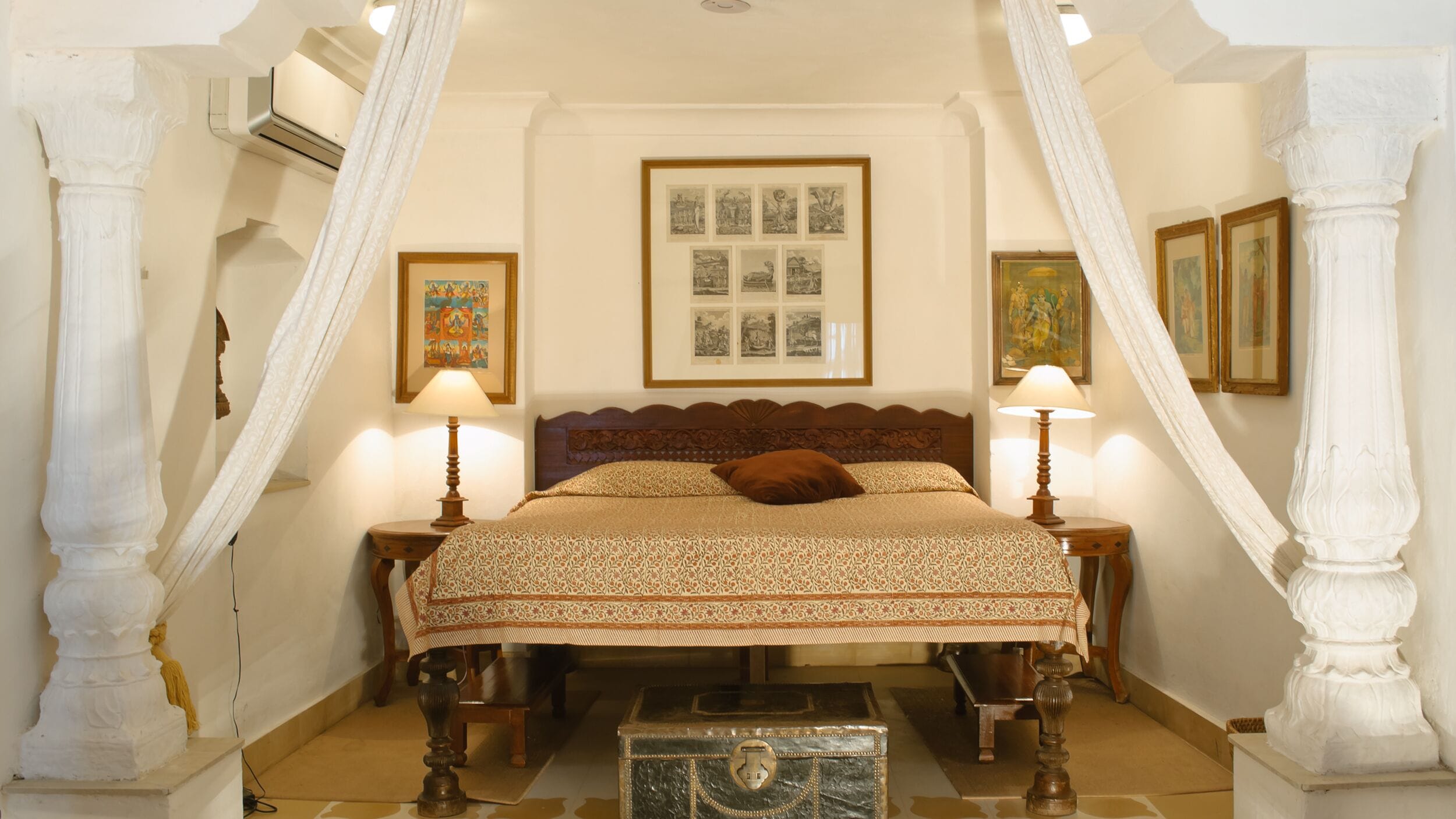 A bedroom with a bed, two bedside tables, a chest of drawers, and a framed picture collection on the wall.
