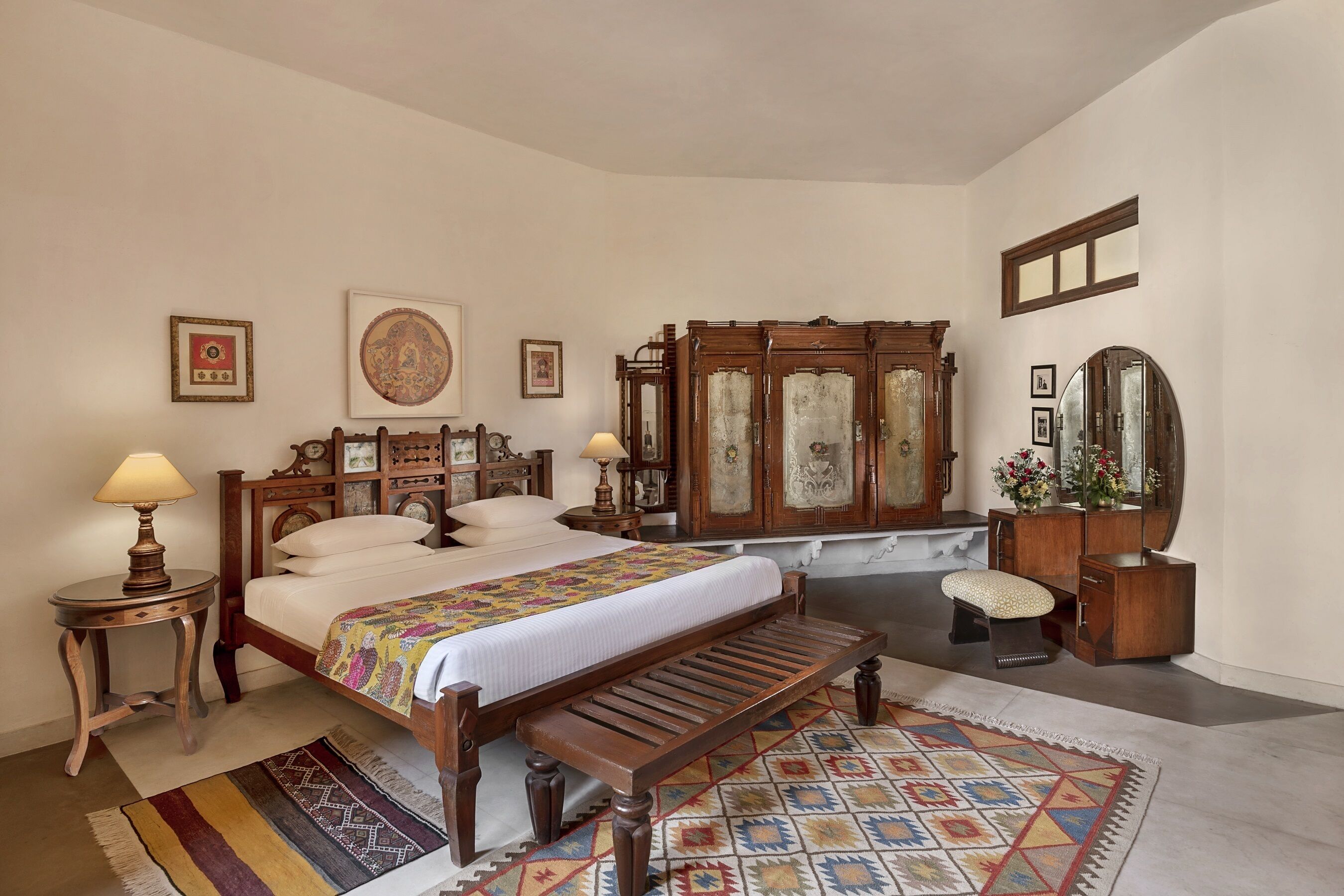 A bedroom with a wooden bed, a bench, a dresser, a mirror, and a rug.