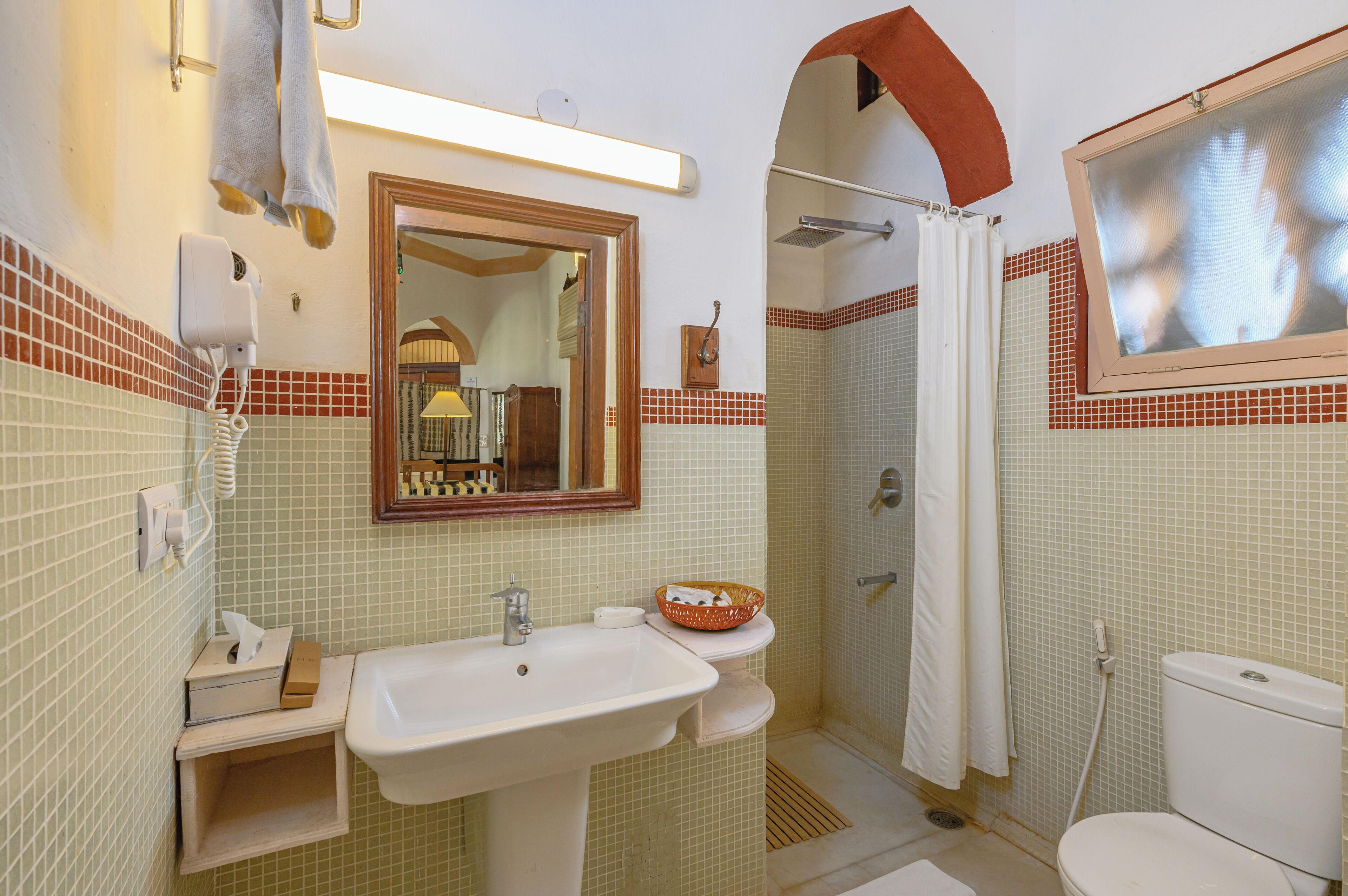 A bathroom with a sink, mirror, shower, and toilet.