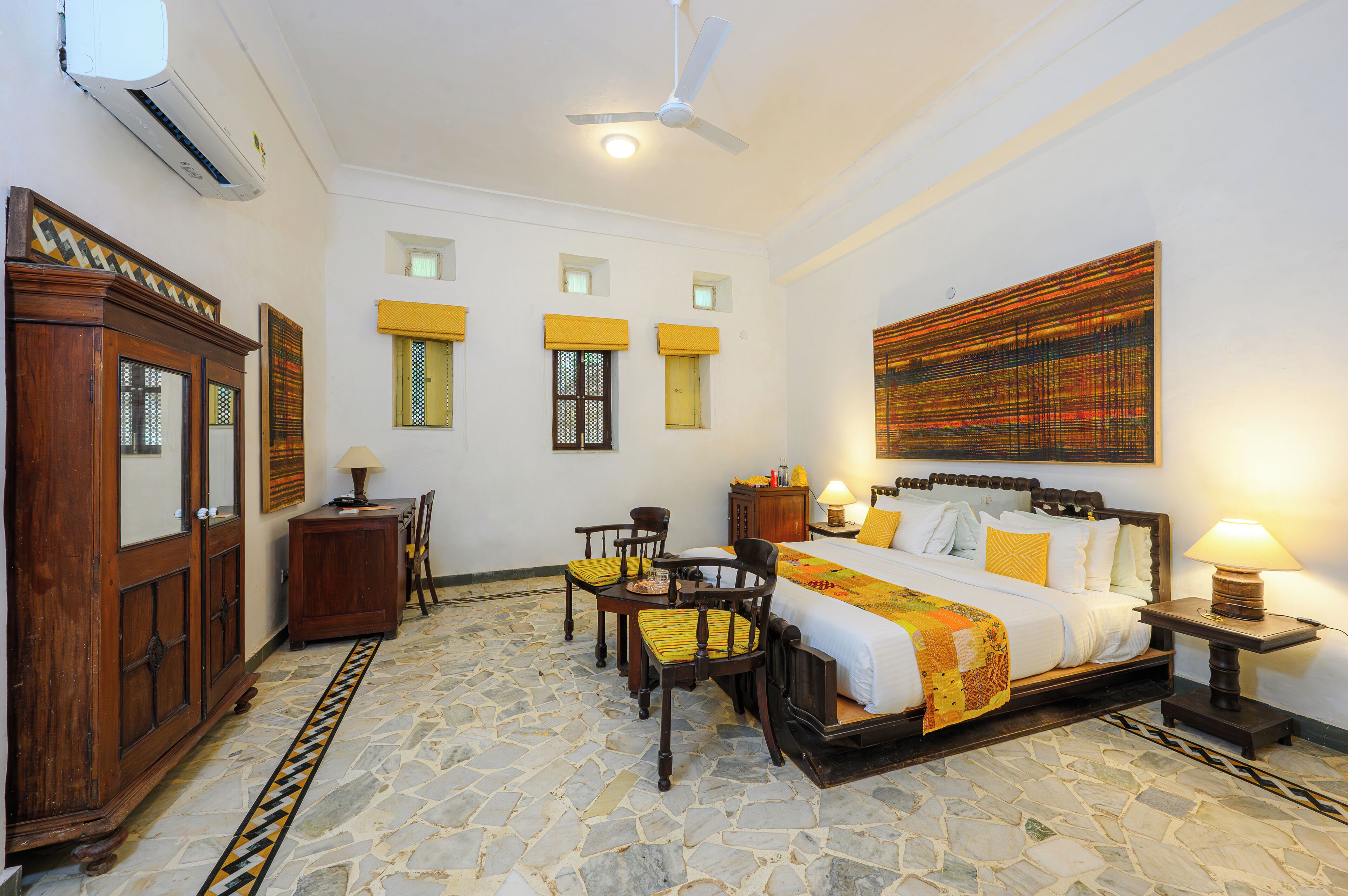 A spacious bedroom with a large bed, a wooden wardrobe, a desk, and a chair.