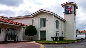 A motel with a prominent '6' sign, a gated entrance, and a parking area. - Motel 6 Euless, TX - DFW West (Euless)