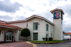 A motel with a prominent '6' sign, a gated entrance, and a parking area. - Motel 6 Euless, TX - DFW West (Euless)