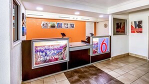 A reception desk with a sign that reads 'We'll leave the light on for you.' - Motel 6 Euless, TX - DFW West (Euless)