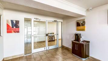 Un hall d’hôtel avec une entrée dotée d’une porte en verre, un distributeur automatique et un espace dédié au café.