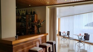 A bar area with a wooden counter, stools, and a variety of bottles.
