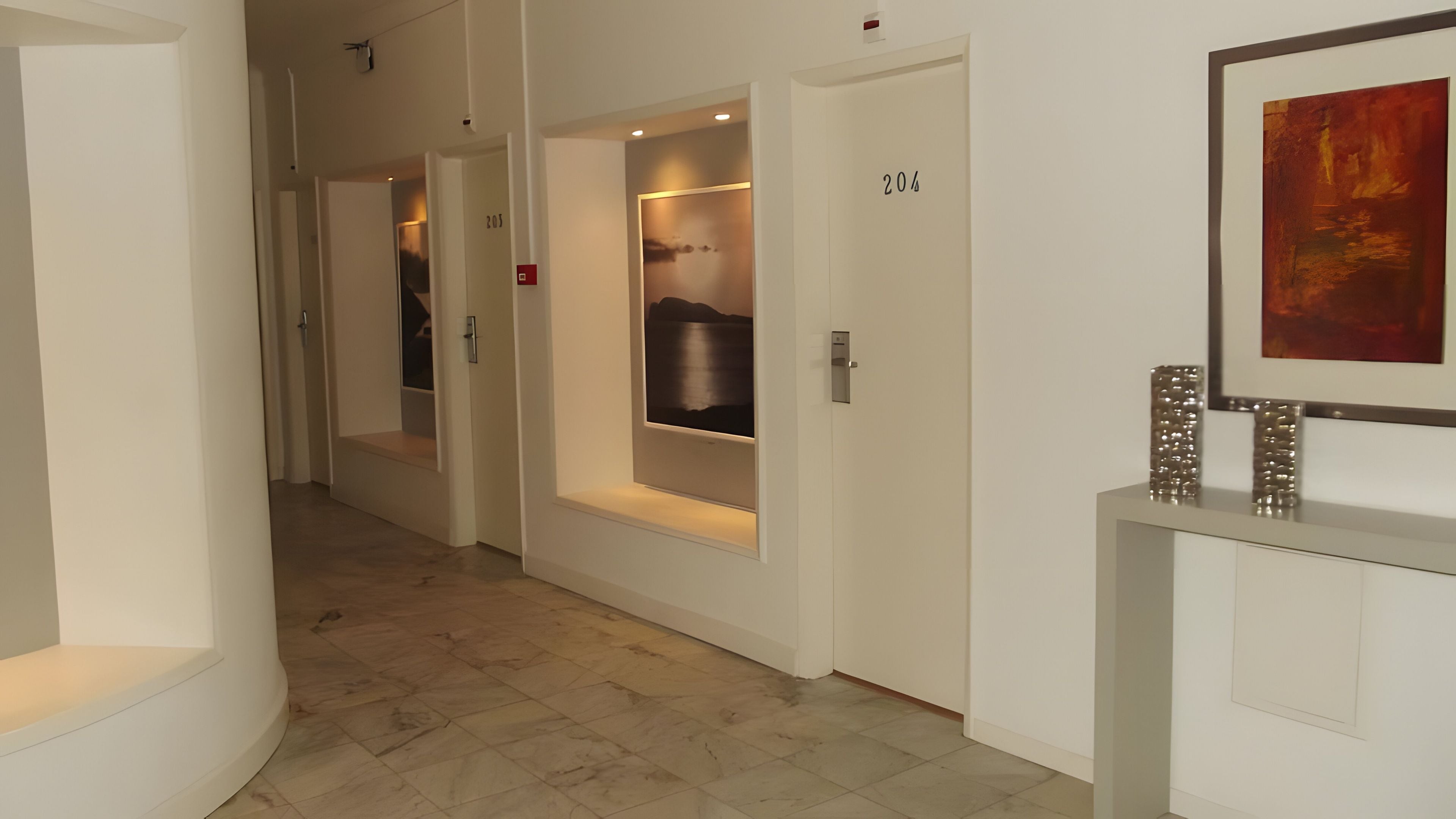 Een hotelhal met een marmeren vloer, een receptiebalie en een ingelijst kunstwerk aan de muur.