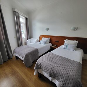 A hotel room with two beds, a chair, and a window with curtains. - Beira Mar (Angra do Heroismo)