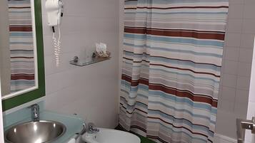 A bathroom with a sink, bidet, toilet, and a striped shower curtain.
