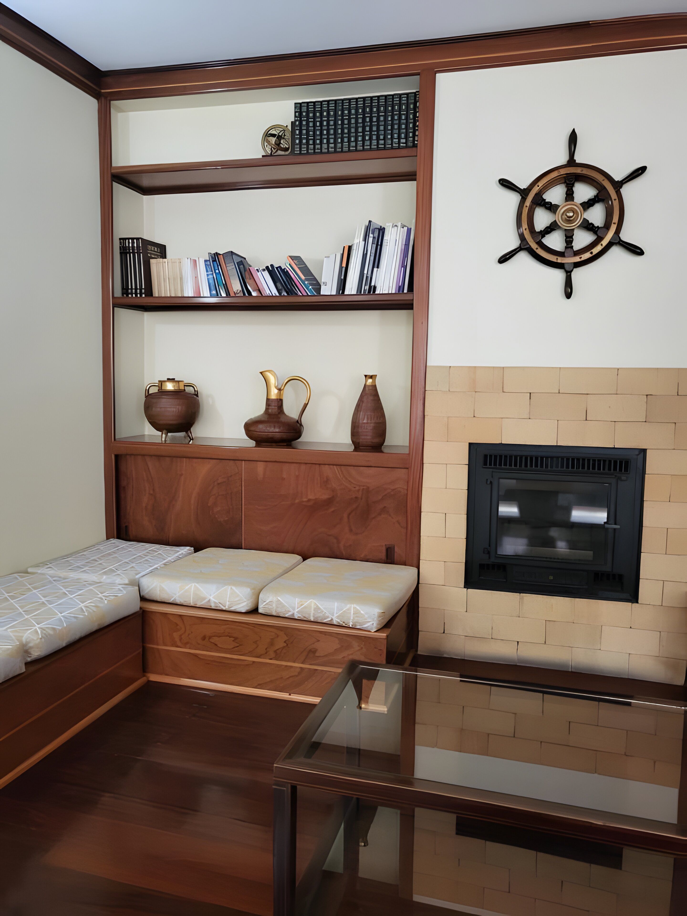 Una habitación con estantería empotrada, chimenea, mesa de vidrio y cama con cabecera.