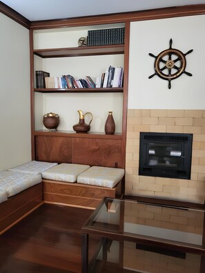 A room with a built-in bookshelf, a fireplace, a glass table, and a bed with a headboard. - Hotel Beira Mar (Angra do Heroismo)