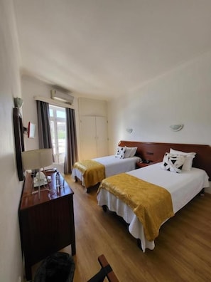 A hotel room with two beds, a desk, a chair, and a wardrobe. - Beira Mar (Angra do Heroismo)