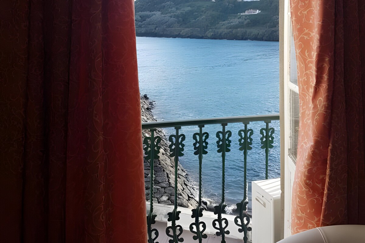 Una habitación con vista a un cuerpo de agua y una colina.