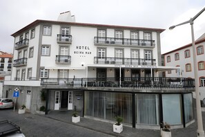 A multi-story hotel with balconies, a ground-level restaurant, and a sign indicating a handicap-accessible entrance. - Hotel Beira Mar (Angra do Heroismo)