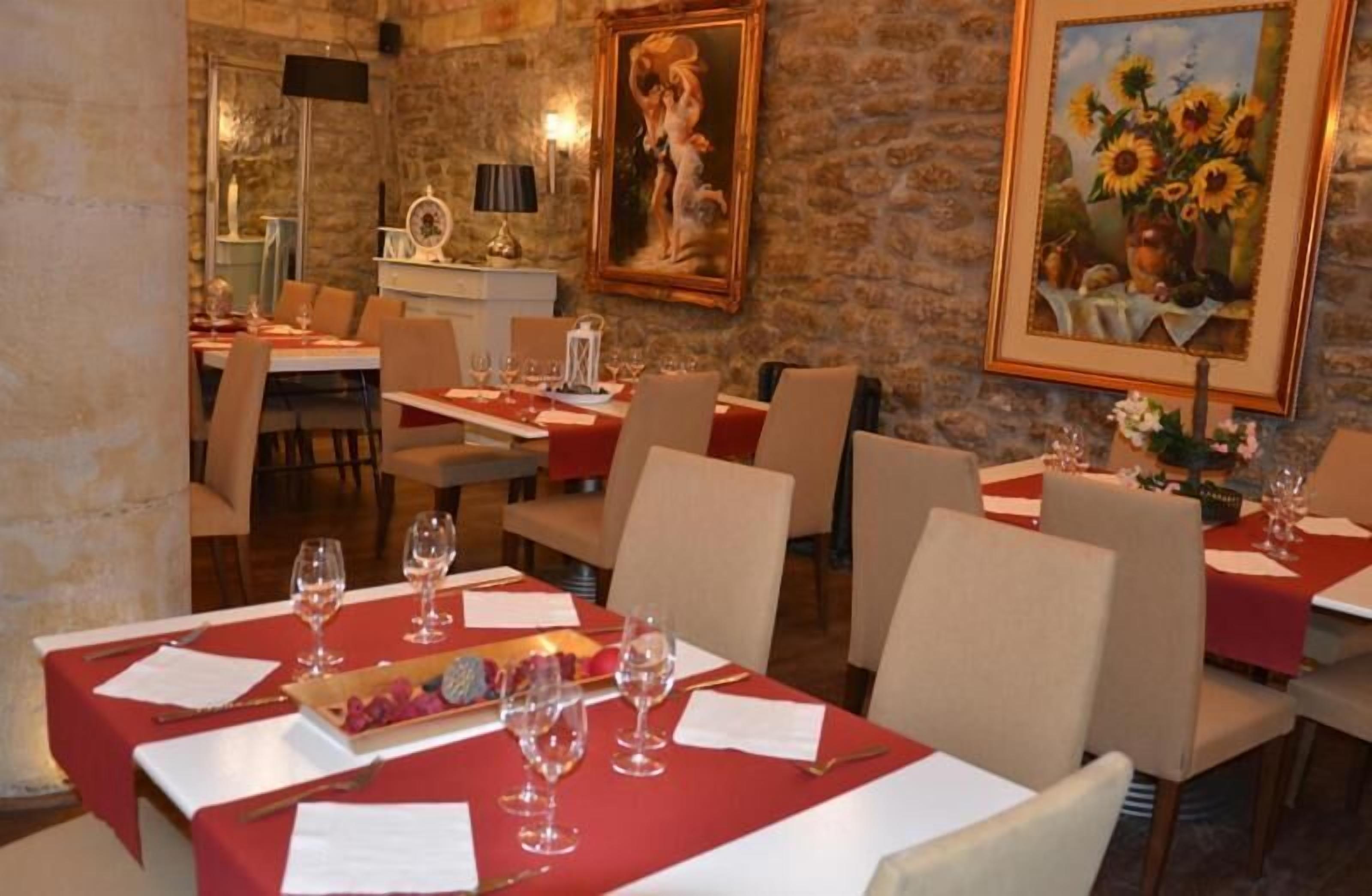 Un espace repas avec des tables dressées pour le service, agrémenté de nappes rouges et de verres à vin.