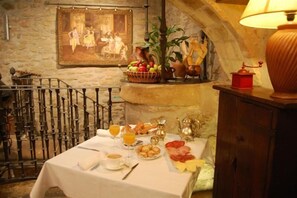 A breakfast table set with various foods, a painting on the wall, and a lamp. - Hostal Rural Bidean (Puente La Reina)