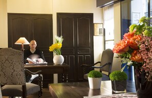 A room with a wooden desk, two chairs, a lamp, and a vase with flowers. - Castex Hotel (Paris)