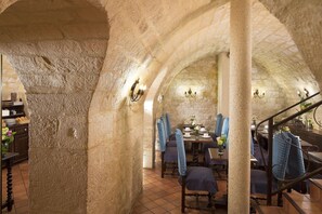 An interior with stone arches, a dining area with blue chairs, and a staircase. - Castex Hotel (Paris)
