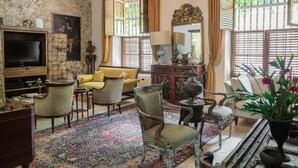 A traditional living room with a television, sofas, and a patterned rug. - Hotel Casa Mejía (Cartagena)