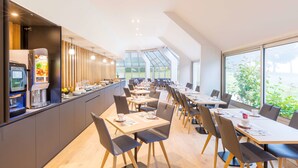 Een moderne eethoek met een lange toonbank, meerdere tafels en stoelen.