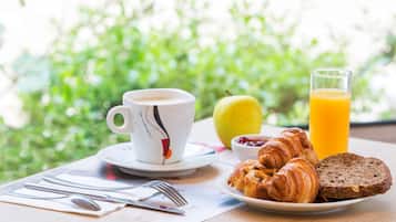 Un esmorzar amb croissants, un got de suc d'aranja, una tassa i un plat amb una làmina de pa.