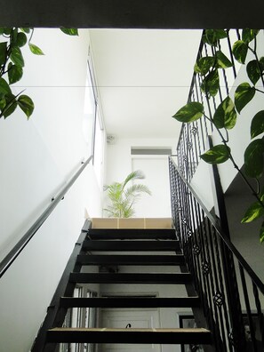 A staircase with a metal railing, a potted plant, and a white door at the bottom. - ARCO Apartasuites (Cali)