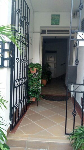A tiled entrance with a black metal gate, potted plants, and a visible door leading to an interior space. - ARCO Apartasuites (Cali)
