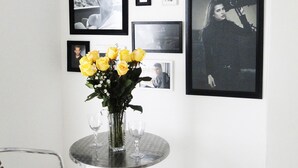 A dining area with a round table, two chairs, and a vase of yellow flowers. - ARCO Apartasuites (Cali)