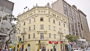 Un edificio histórico con un estilo arquitectónico clásico, que presenta una entrada destacada y una bandera en la parte superior.