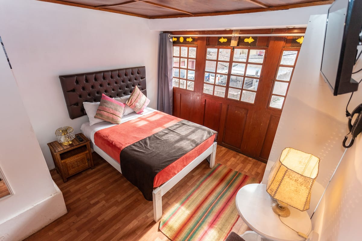 A bedroom with a bed, bedside table, and a window with curtains.