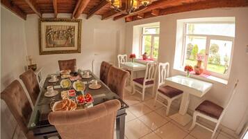 A dining area with a glass table, white chairs, and a wooden ceiling.