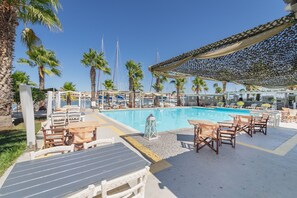 Una piscina al aire libre, sombrillas, sillones reclinables de piscina