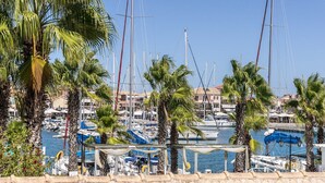 Un puerto deportivo con barcos amarrados, palmeras y edificios al fondo.