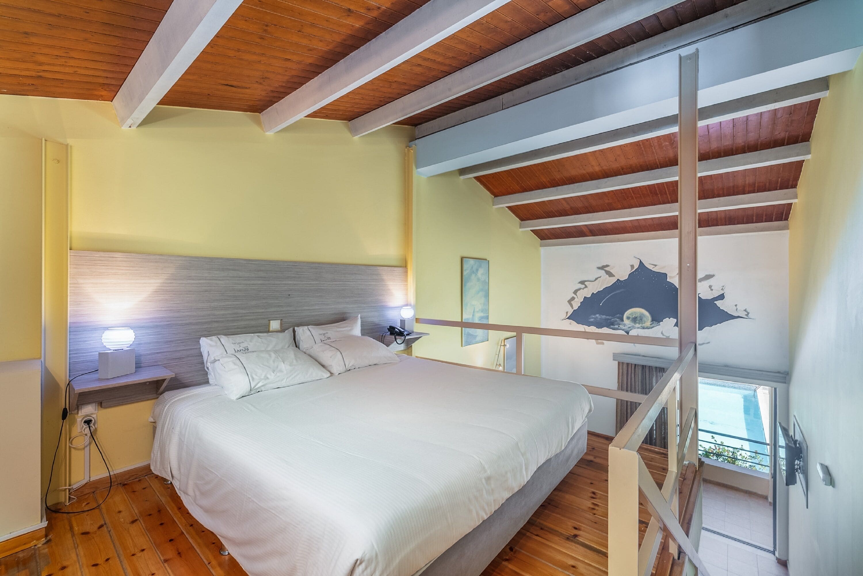Une chambre à coucher avec un lit, des lampes de chevet, une table de nuit et un plafond en bois.