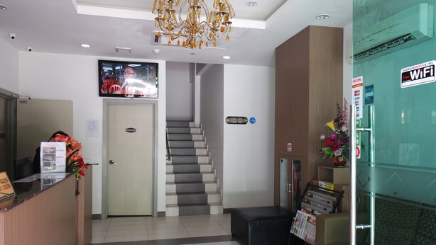 A hotel reception area with a reception desk, a staircase, and a WiFi sign.