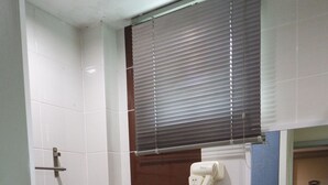 A bathroom with a toilet, sink, and a hairdryer on the wall.