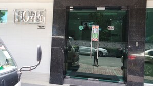A hotel entrance with a glass door, a 'HOME HOTEL' sign, and a 'LAGUAN SOLIDHND' sign.