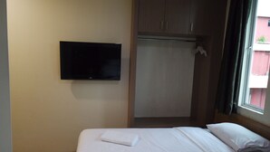 A hotel room with a bed, a television mounted on the wall, and a window with curtains.