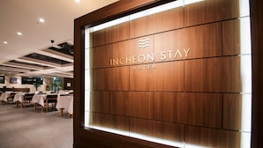 A hotel reception area with a wooden panel wall displaying the name "INCHEON STAY HOTEL". - Incheon STAY Hotel (Incheon)