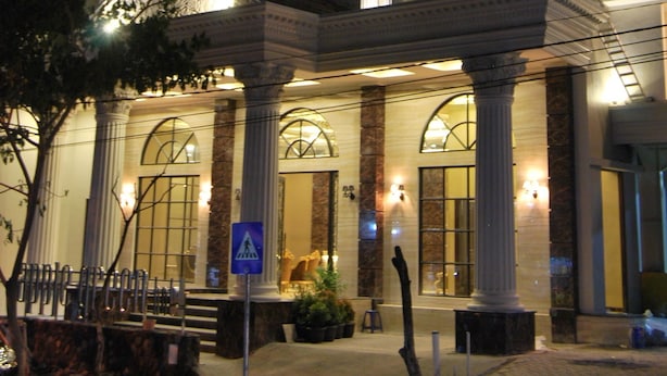 Um hotel imponente com arquitetura clássica, apresentando vários andares, colunas grandes e janelas em arco.