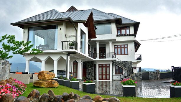 Een huis met twee verdiepingen, een groot balkon, een gevel van natuursteen en uitzicht op het water.