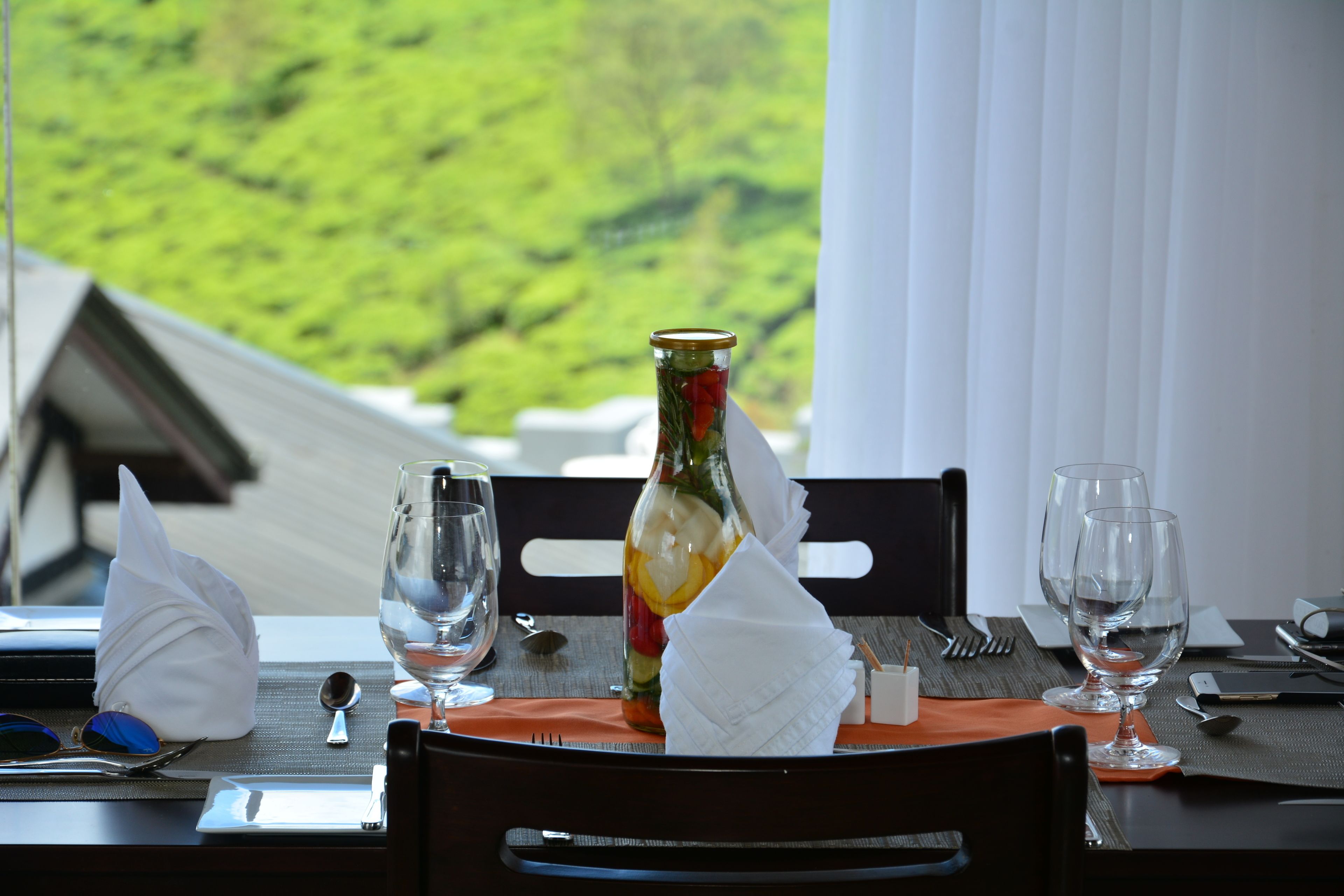 A dining table set with a bottle of wine, two glasses, a folded napkin, and cutlery.