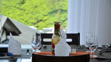 A dining table set with a bottle of wine, two glasses, a folded napkin, and cutlery.